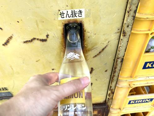 懐かしの瓶ジュース自販機、栓抜きを使う